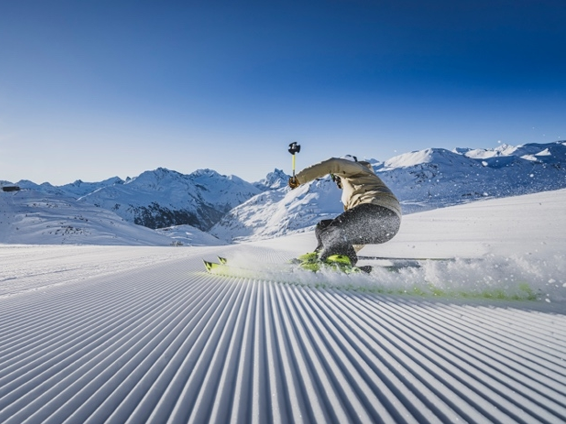 Skifahrer beim Carven auf frisch präparierter Skipiste in den Bergen